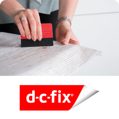 Aplicación de la película adhesiva dc-fix con una espátula para obtener un acabado suave en superficies de madera clara.